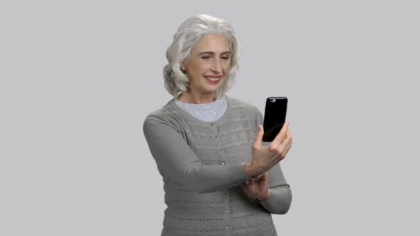 Vieille dame prenant des photos selfie verticales et horizontales sur sa caméra frontale . — Video