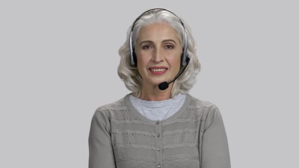 Senhora muito sênior usando fone de ouvido e sorrindo . — Vídeo de Stock