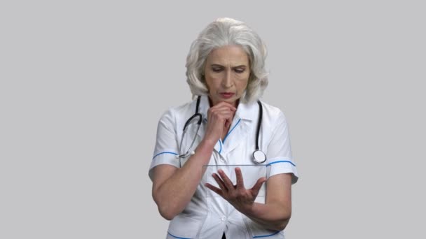 Allvarlig senior kvinnlig läkare med glas mockup tablett pc anordning. — Stockvideo