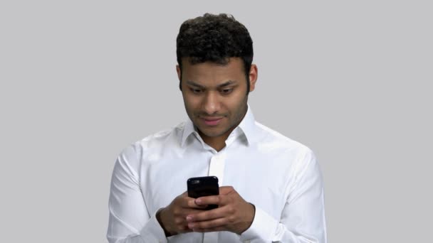 Portrait of dark-skinned young guy typing message on his smartphone. — Stock Video