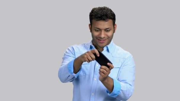 Excited young dark-skinned guy playing smartphoe game. — Stock Video