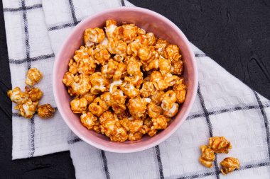 Yakın plan altın patlamış mısır seramik tabakta ve kareli arka planda.