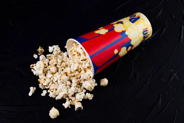 Smaklig popcorn spills från en välvd låda mörk bakgrund. — Stockfoto
