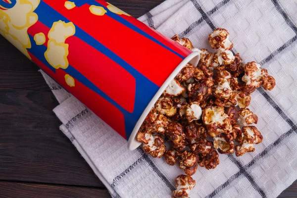 Schoko-Popcorn aus Eimer auf Handtuch verstreut. — Stockfoto