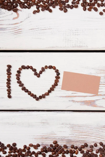 Letter I and heart frame shaped coffee beans with blank paper.