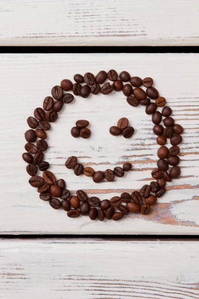 Kávová zrna na bílých prknech uspořádané ve tvaru úsměvu tvář. — Stock fotografie
