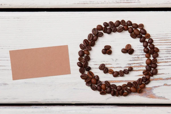 Usmívající se obličej z kávových zrn a prázdný papír pro kopírovací prostor. — Stock fotografie