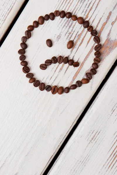 Vertical image sad coffee bean smiley face on wood.