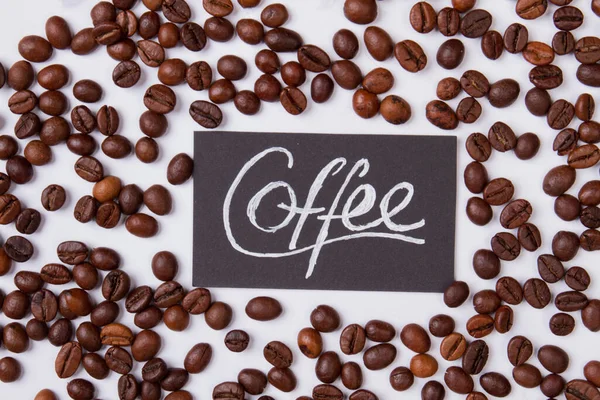 Coffee word and roasted beans scattered around. — Stock Photo, Image