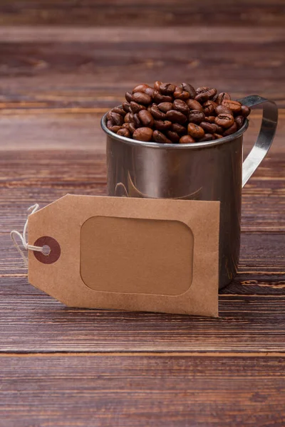 Tasse en acier avec grains de café et étiquette pour l'espace de copie . — Photo
