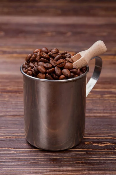 Grains de café marron dans une tasse en acier avec une cuillère en bois . — Photo