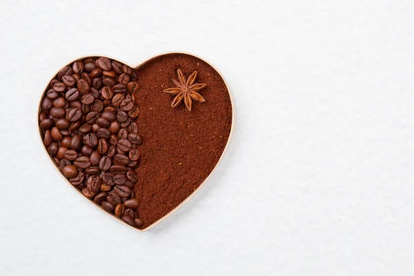 Кофейные зерна и порошок в форме сердца . — стоковое фото