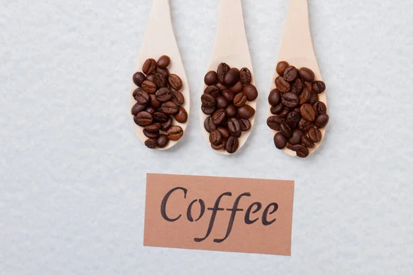 Reihe von drei Holzlöffeln mit Kaffeebohnen. — Stockfoto
