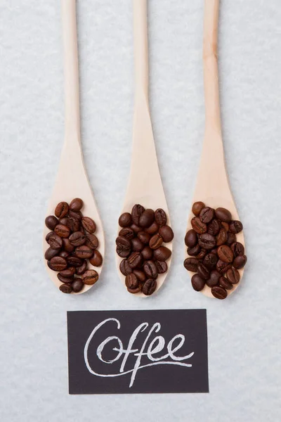 Poignée de grains de café sur cuillères en bois . — Photo