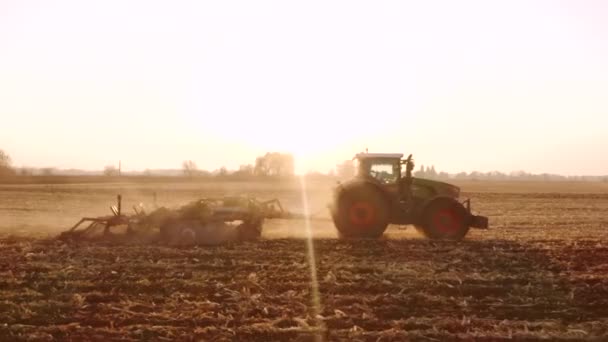 Tractor trabajando en el campo al amanecer . — Vídeos de Stock