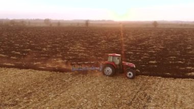 Kırmızı modern traktör ekmeden önce toprağı sürüyor..