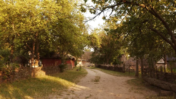 Carretera arenosa rural y edificios del pueblo cercados por valla de ripio . —  Fotos de Stock