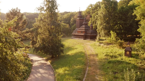 Brązowy drewniany kościół z trzema kopułami w lesie i asfaltowej drodze. — Zdjęcie stockowe