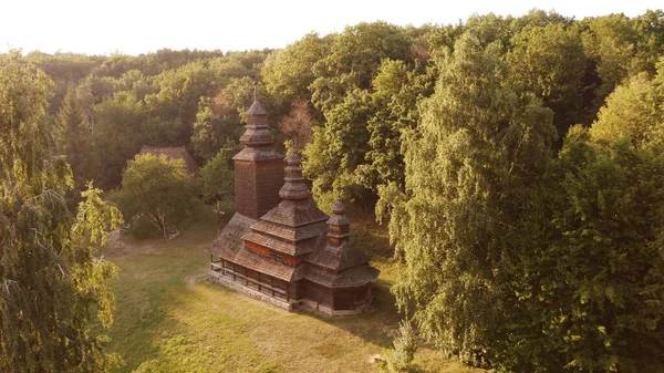 Brown wooden church with three domes in the forest. — Stock Photo, Image