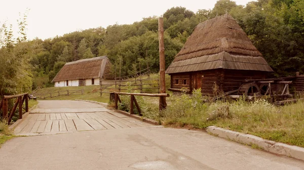 Jalan Asphalt dengan jembatan kayu kecil dan desa. — Stok Foto