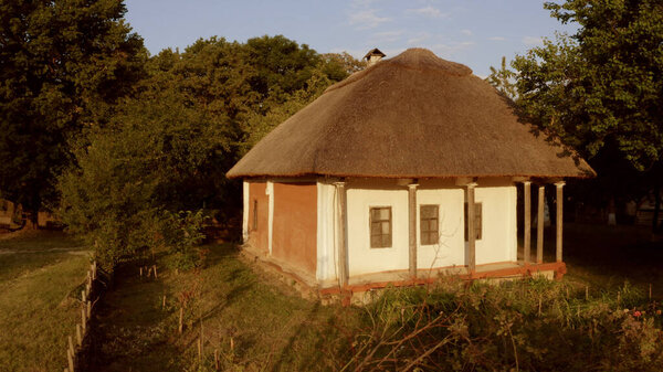 Small house with columns in the village. Roof is thatched.