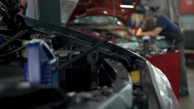 Bir servis merkezinde profesyonel tamirci araba tamir ediyor..