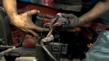 Kirli elli tamirci araba motoru detaylarını söküp onarıyor.