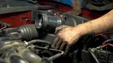 Genç profesyonel araba servisi çalışanı araba motoru detaylarını yüklüyor..
