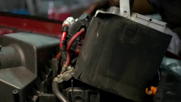 Autoservicemedewerker die een accu in een automotor installeert. — Stockvideo
