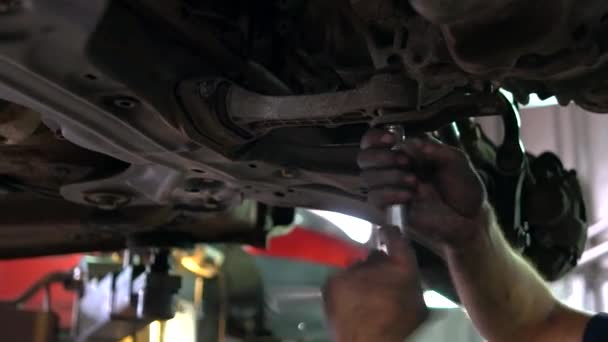 Mechanik wkręca śrubę w spodzie samochodu.. — Wideo stockowe