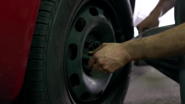Aanscherping van de moeren in het autowiel. — Stockvideo