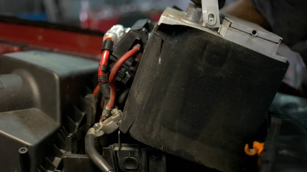 Pracovník autoservisu instalující akumulátor do automobilového motoru. — Stock fotografie