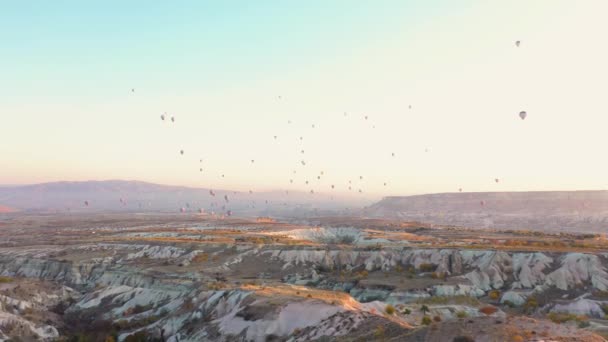 Globos de aire caliente volando sobre el paisaje rocoso en Capadocia . — Vídeos de Stock