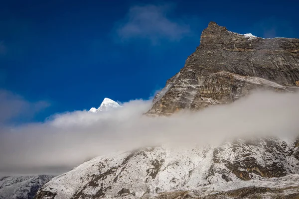 Mooie rots top tegen wolken en sneeuw — Stockfoto