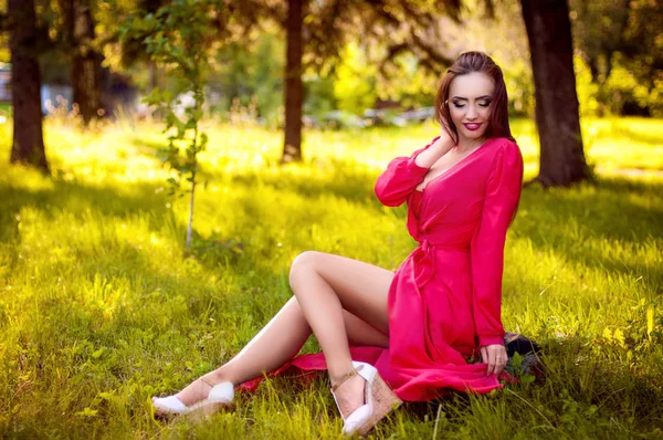 Mulher ruiva jovem atraente com maquiagem beleza situando e posando em vestido vermelho. Ao ar livre — Fotografia de Stock