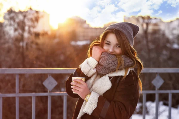 ホットド リンクのカップを保持している少女。彼女の手でコーヒーのマグカップ。都市の冬の路地、街を歩く少女. — ストック写真