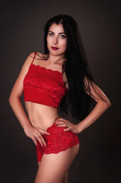 Donna seducente che indossa lingerie rossa sul backround scuro — Foto Stock