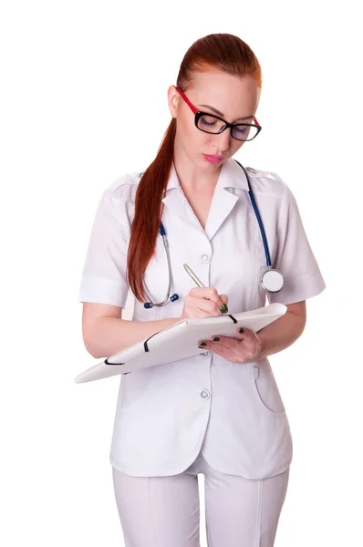Schöne junge Ärztin in medizinischem Gewand, die eine Krankenakte hält. Krankenschwester macht Einträge in Krankenakte — Stockfoto
