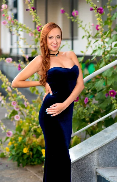 Moda modelo de cabelos vermelhos posando sexy, vestindo vestido de noite longo azul na rua da cidade — Fotografia de Stock