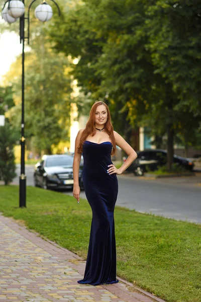 Мода рыжие волосы модель позирует сексуально, в длинном синем вечернем платье на улице города — стоковое фото
