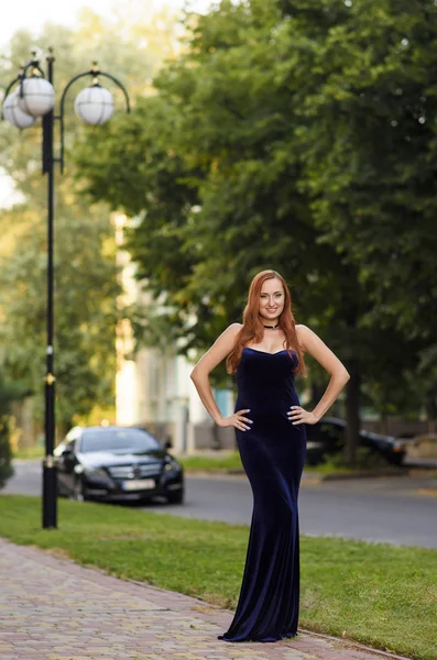 Moda mulher de cabelo vermelho posando sexy, vestindo vestido de noite azul longo na rua da cidade — Fotografia de Stock