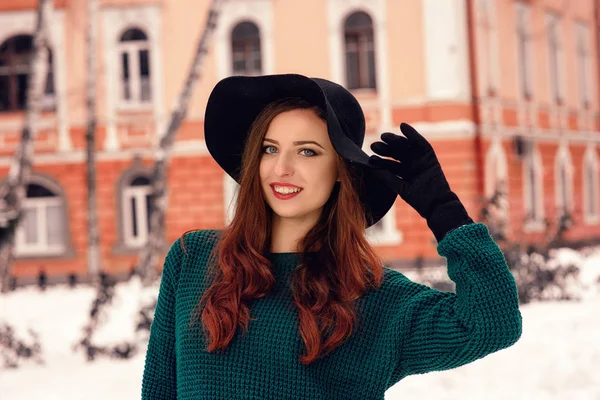 Retrato de cerca de una joven guapa con un suéter caliente, una gorra negra. Retrato de invierno de mujer joven. Fondo de vista de calle —  Fotos de Stock