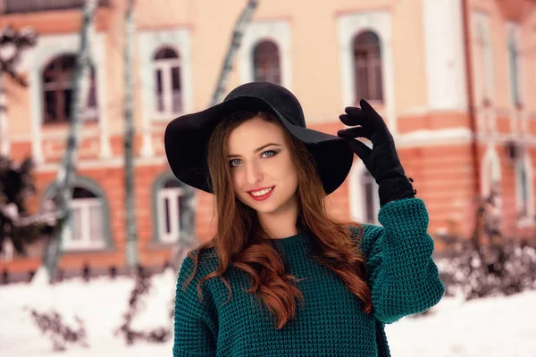 Retrato de cerca de una joven guapa con un suéter caliente, una gorra negra. Retrato de invierno de mujer joven. Fondo de vista de calle —  Fotos de Stock