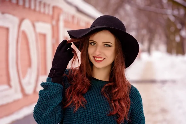 Retrato de close-up de uma jovem menina bonita em uma camisola quente, um boné preto. Retrato de inverno de mulher jovem. Rua vista de fundo — Fotografia de Stock