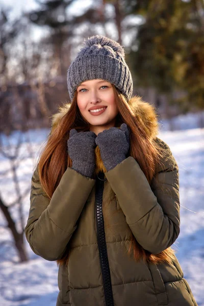 Mujer atractiva joven vestida caliente en abrigo, sombrero y guantes, disfrutando del sol de invierno y sonriendo —  Fotos de Stock