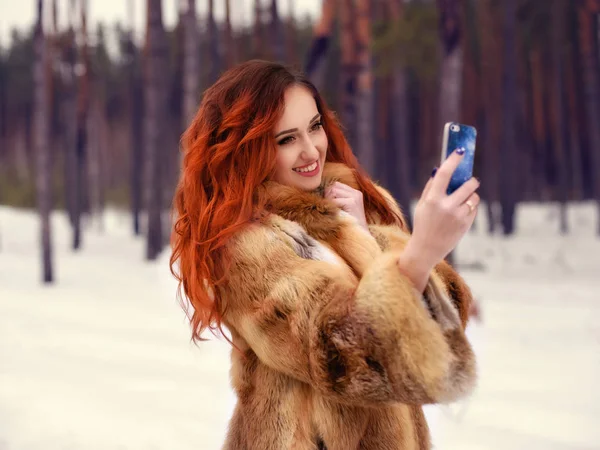 Mooie jonge rode haar vrouw maken selfie in winter park — Stockfoto