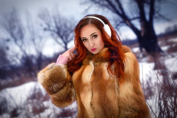 冬の公園を歩いてかなり魅力的な女性。彼女は音楽を聴いています。戸外で歩く. — ストック写真