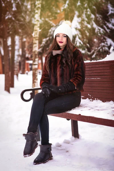 Piękny i sexy kobieta siedzi na ławce w śnieg na zewnątrz — Zdjęcie stockowe