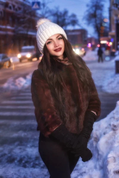 Fiatal szép boldog mosolygó lány pózol utcában este. Nézi a kamera modell. Nő visel elegáns téli ruhák — Stock Fotó