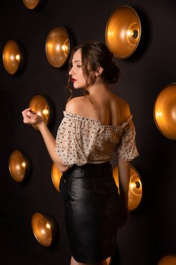 Siyah deri etekli güzel bir kadın moda stüdyosunda poz veriyor.